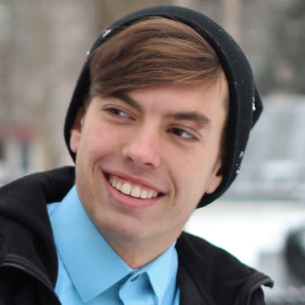 Portrait standing in for Jacob Anderson: a smiling young man in a dark beanie.